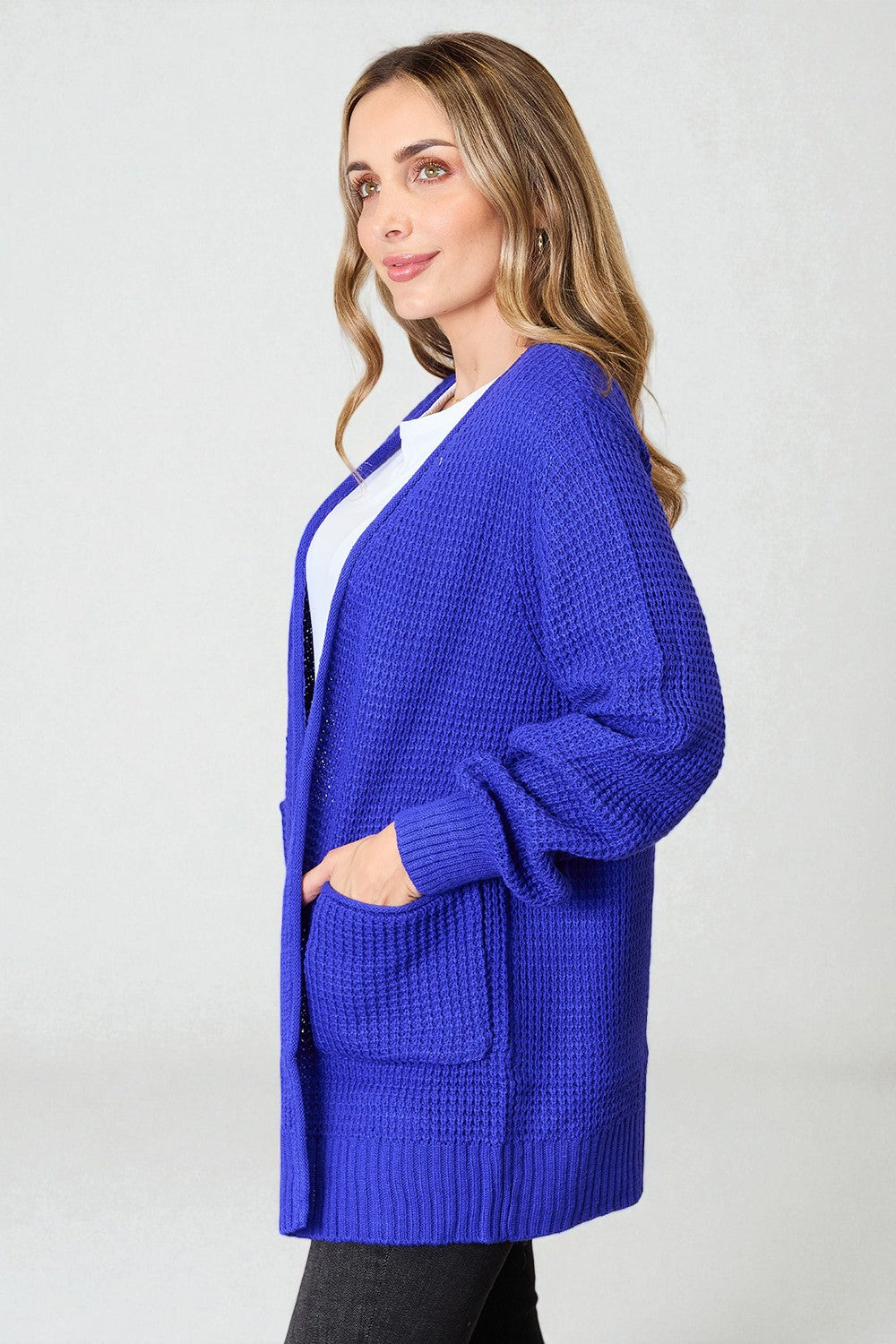 Woman wearing a blue cardigan on a plain background