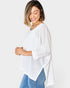 Woman wearing a white knit sweater and blue jeans on a plain background