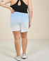 Person wearing a black tank top and light blue to white ombre shorts on a beige background