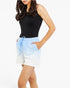 A woman wearing a black sleeveless top and light blue and white ombre shorts with a drawstring waist, shown against a plain white studio background.