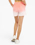 A person wearing tie-dye athletic shorts with a pink-to-white gradient, shown from the back against a plain white studio background.
