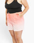 A person wearing pink ombre shorts with a drawstring waist and a black tank top, shown from the chest down against a plain light background.