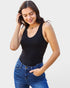 Woman wearing a black tank top and blue jeans against a light gray background