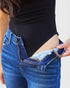 Person wearing blue jeans with a black top, showing the back pocket.