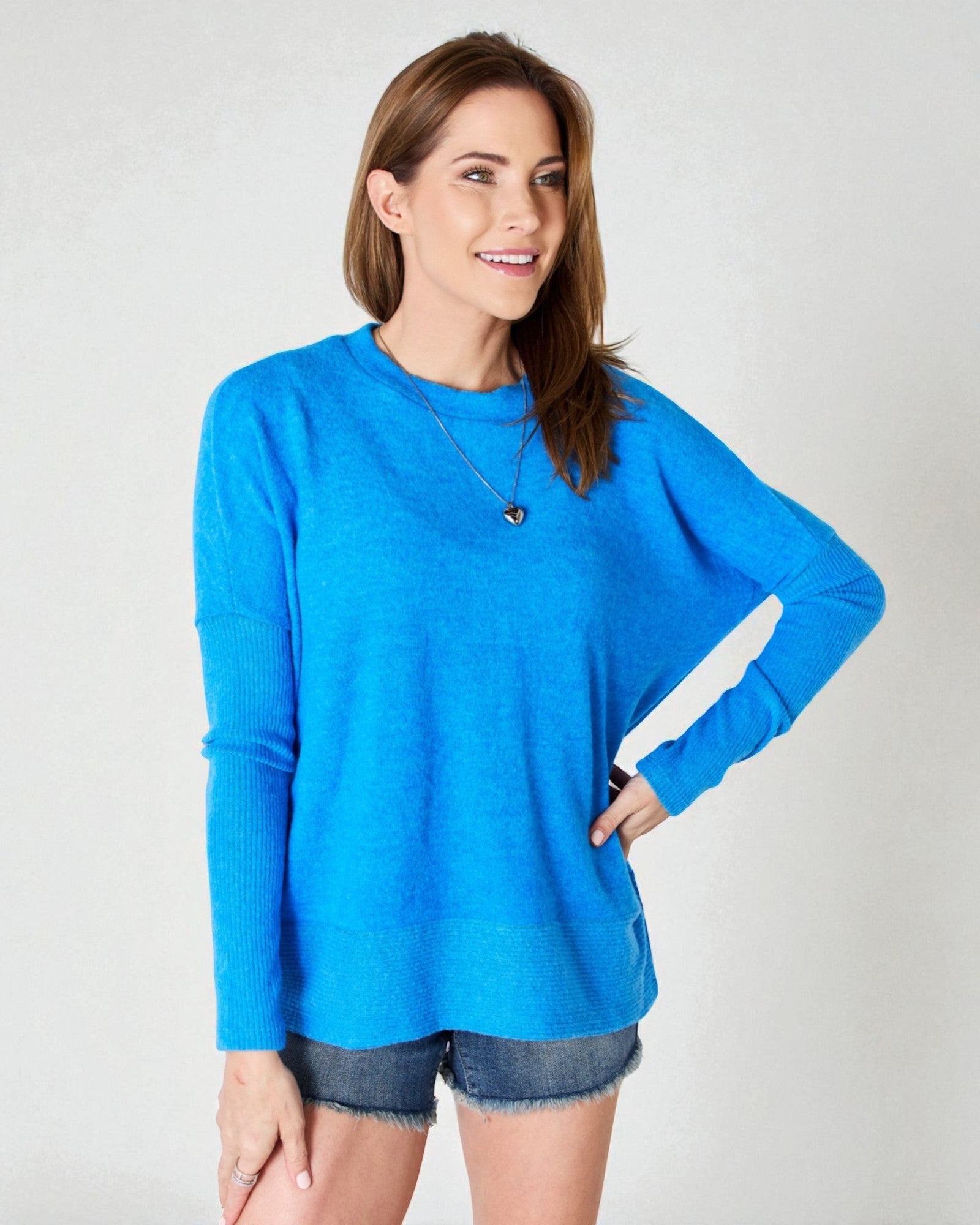 Woman wearing a blue long-sleeve top against a plain background