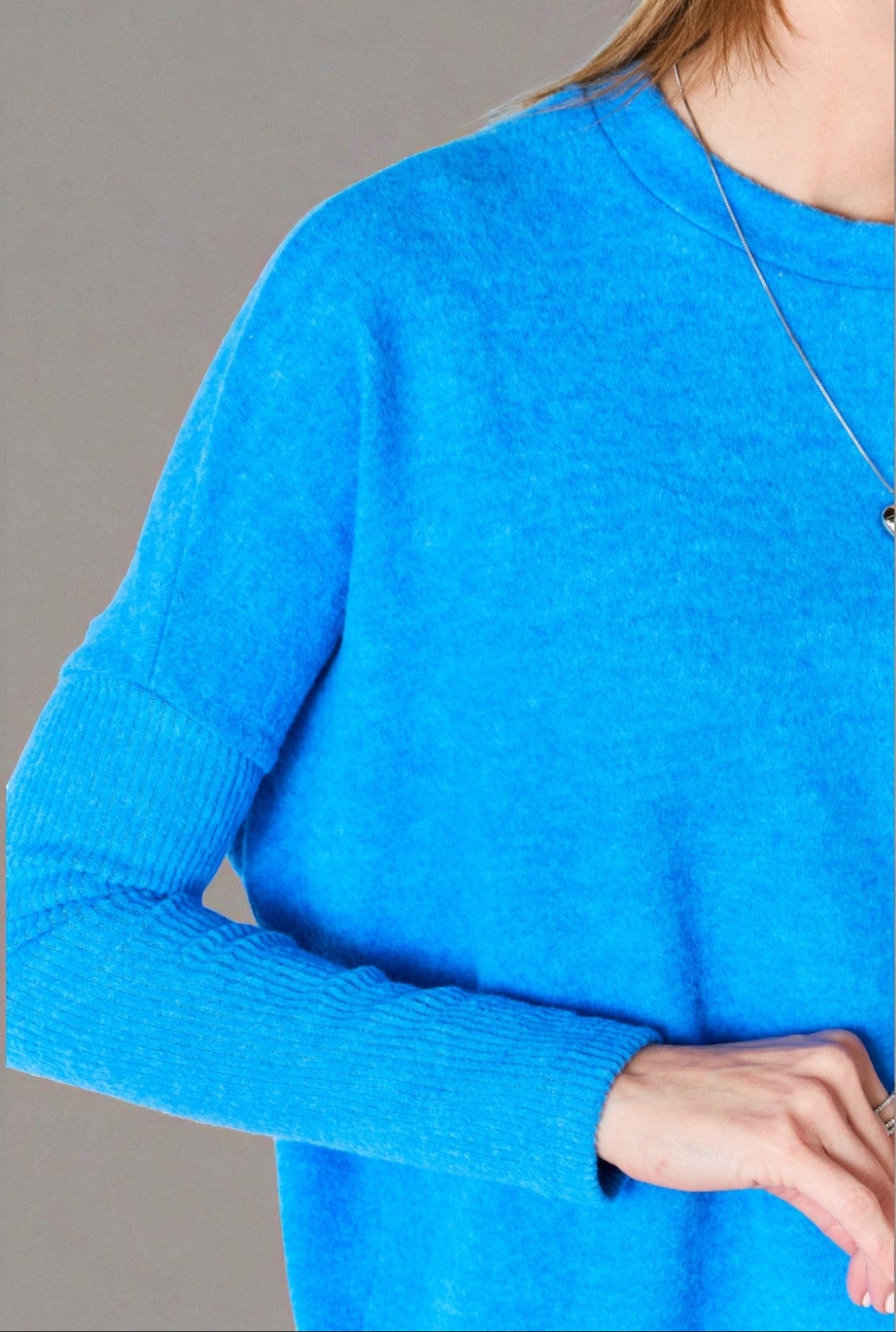 Blue sweater worn by a person on a gray background