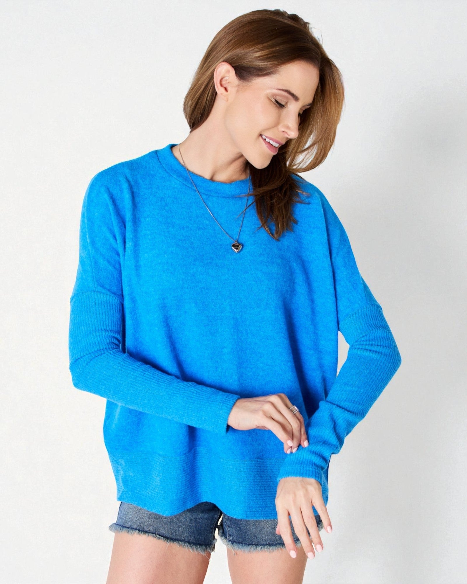 Woman wearing a blue sweater and denim shorts on a white background