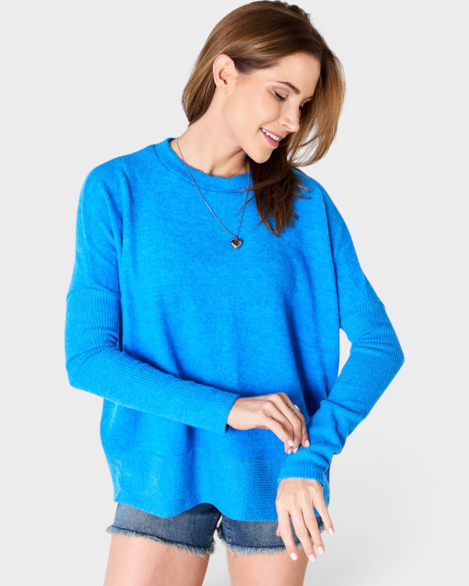 Woman wearing a blue sweater and denim shorts on a white background