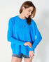 Woman wearing a blue sweater and denim shorts on a white background