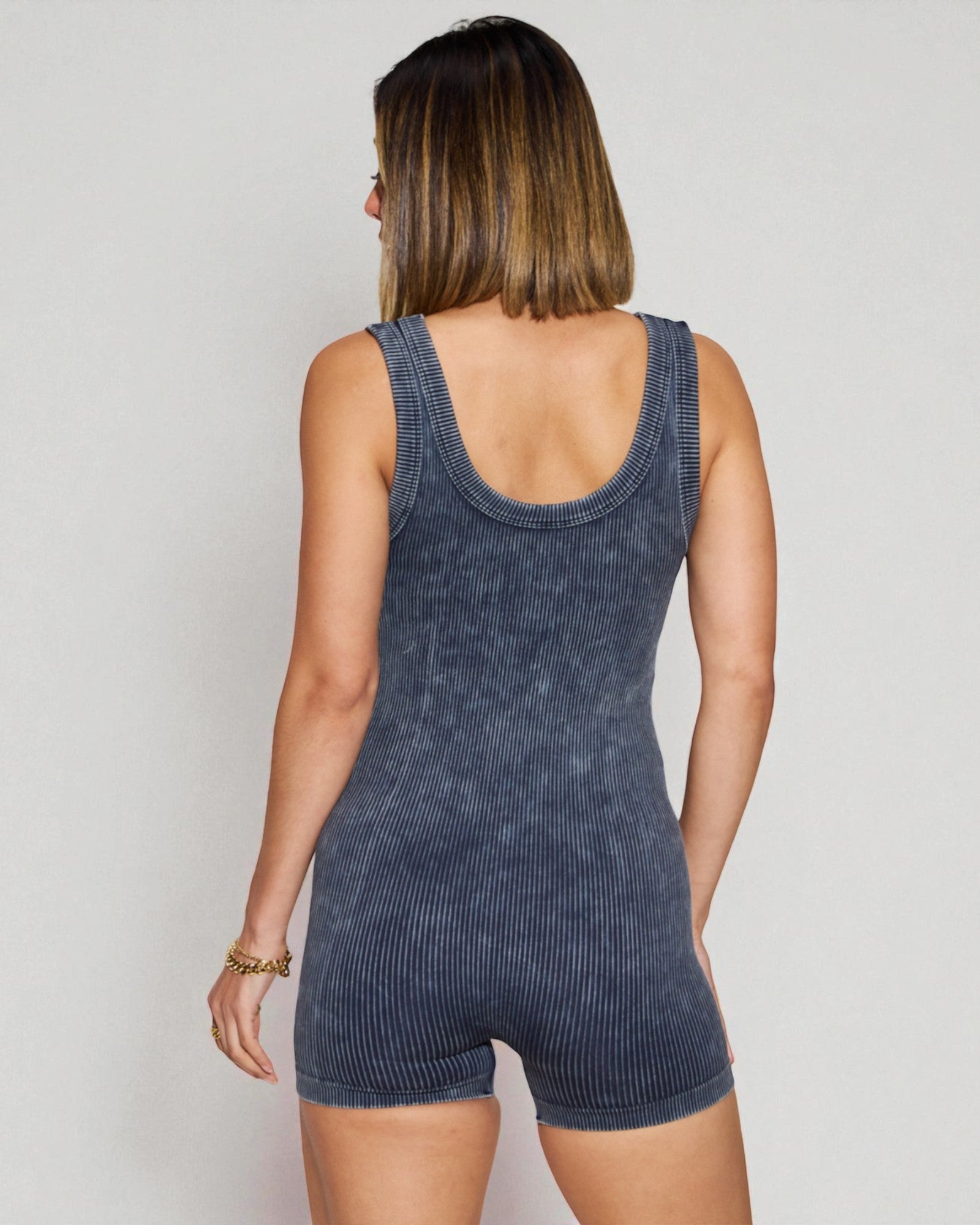 Woman wearing a blue ribbed romper against a plain background