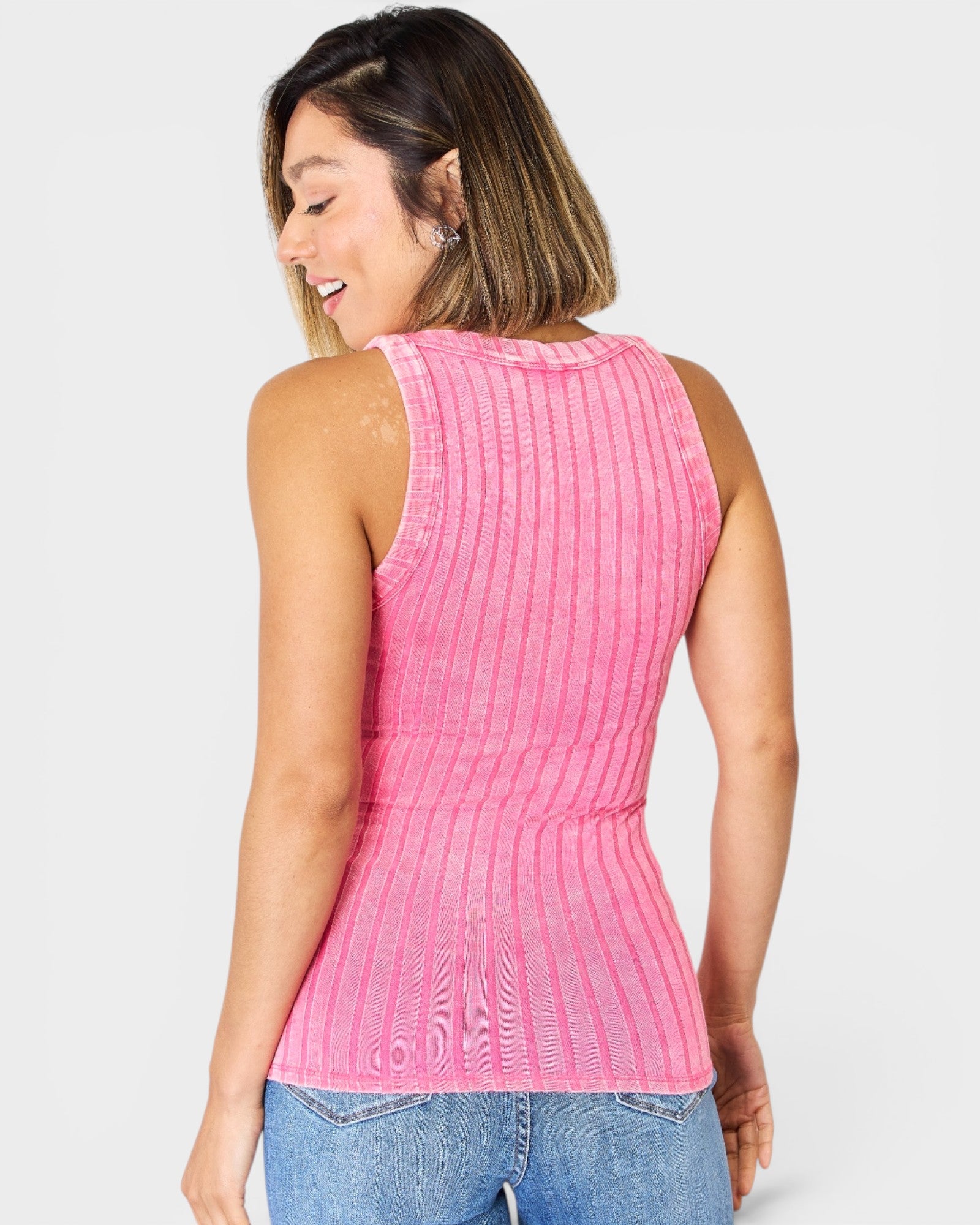 Woman wearing a pink sleeveless top with a textured pattern on a light gray background