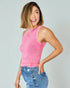 Woman wearing a pink sleeveless top and blue jeans against a light gray background