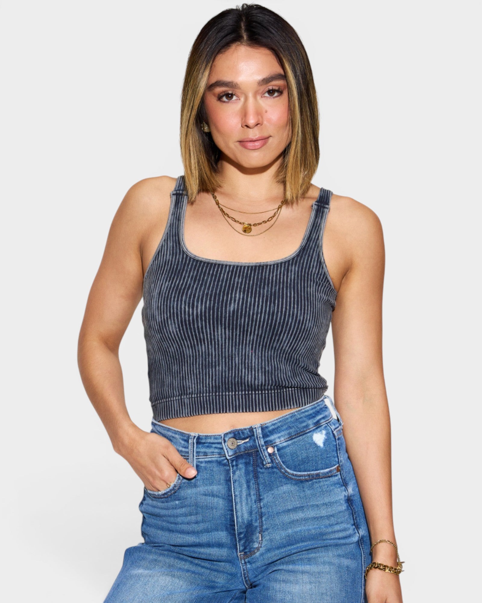Woman wearing a denim tank top and jeans on a plain background