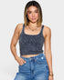 Woman wearing a denim tank top and jeans on a plain background