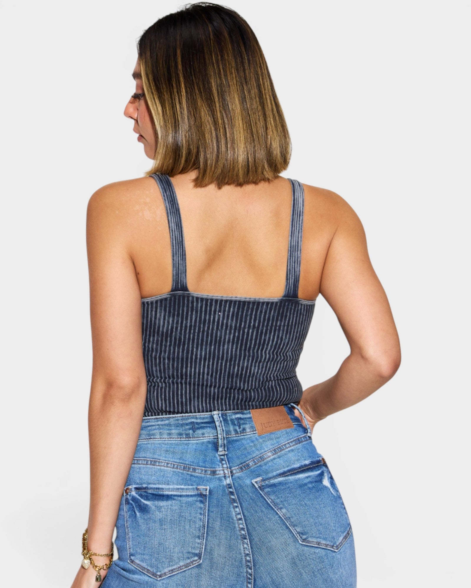 Woman wearing a denim crop top and jeans on a plain background