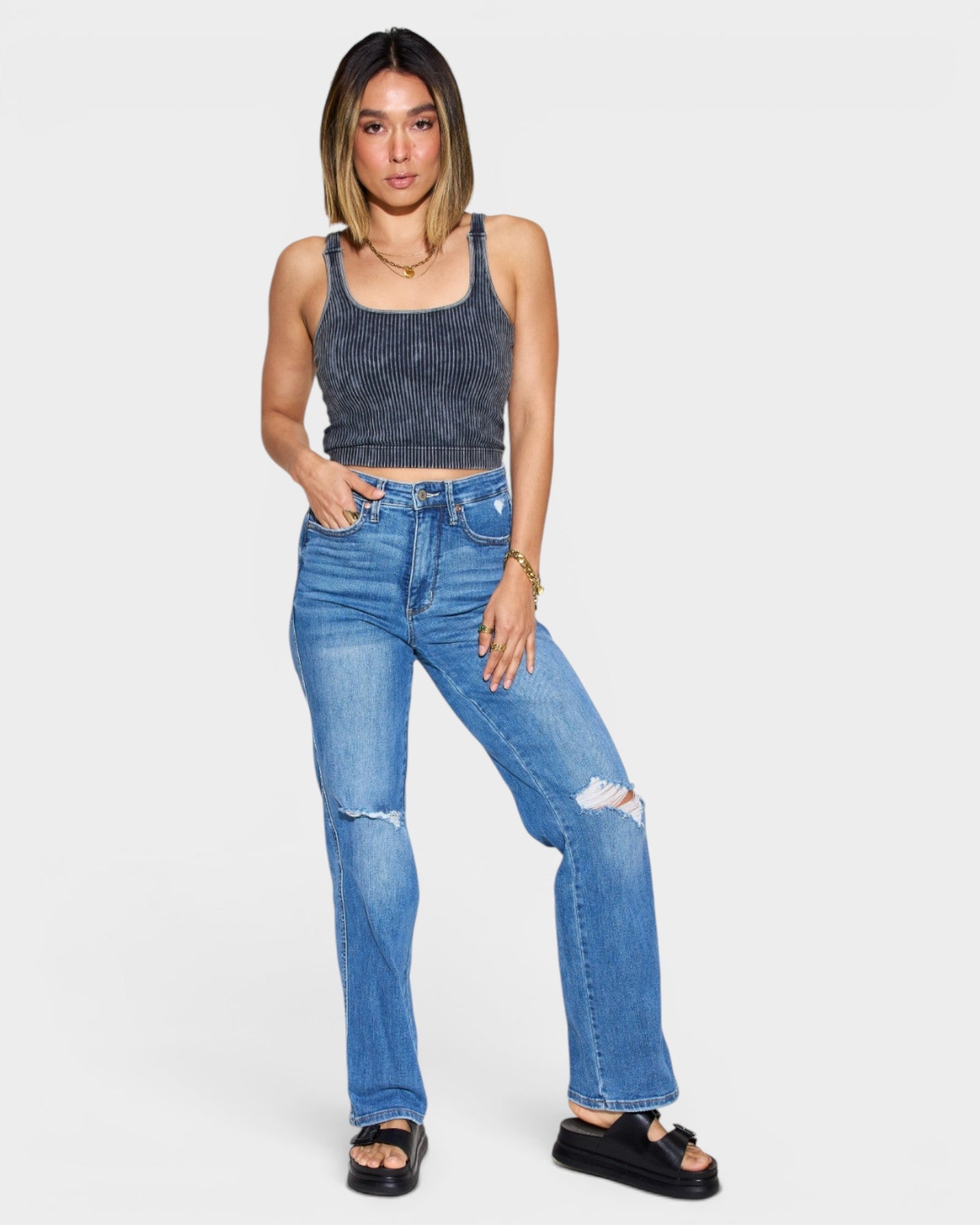 Woman wearing a blue tank top and jeans on a white background