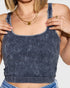 Person wearing a blue ribbed tank top with a plain background