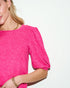 Close-up of a person wearing a bright pink top with a plain background