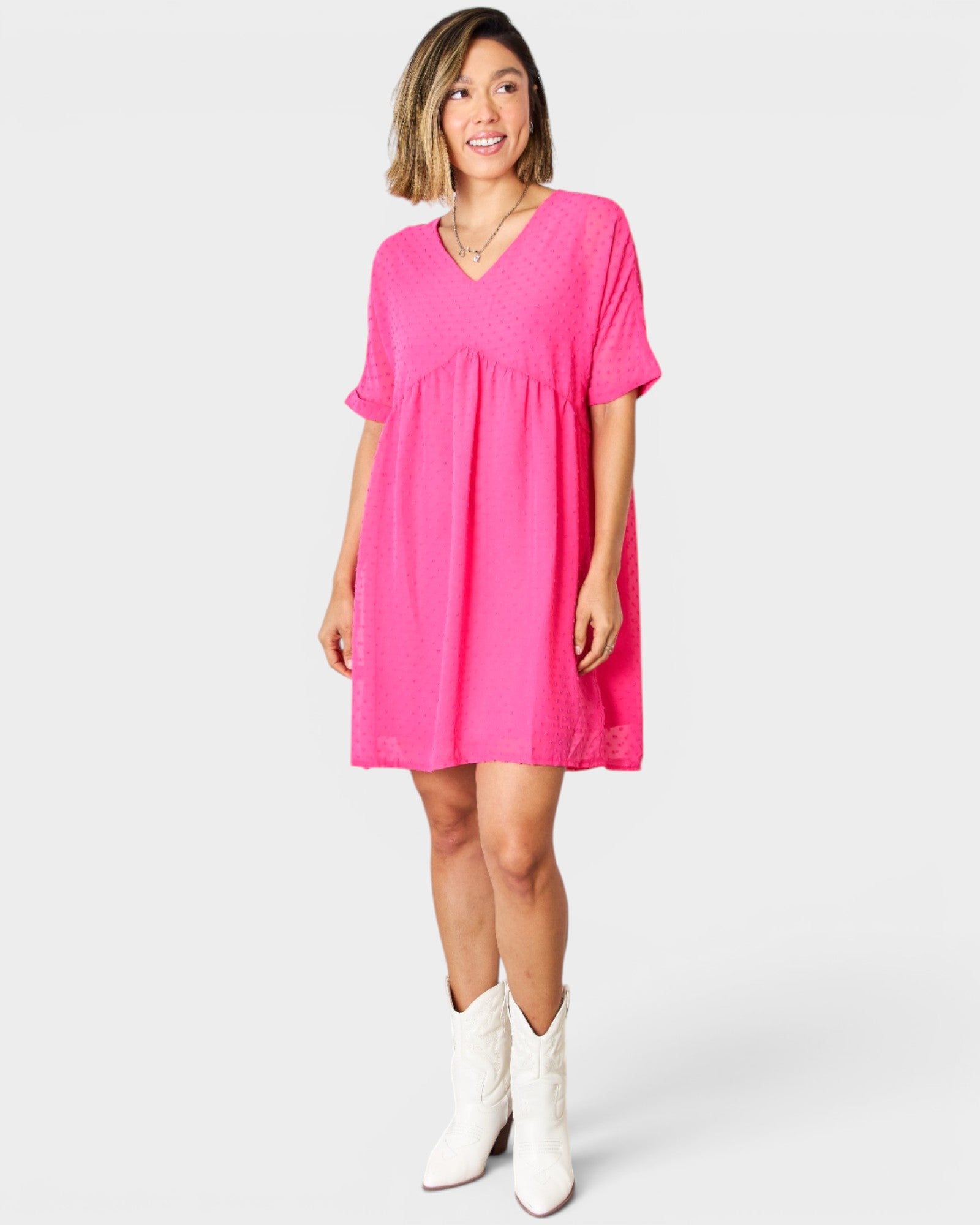 Woman wearing a bright pink dress with white boots on a white background