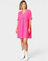 Woman wearing a bright pink dress with white boots on a white background