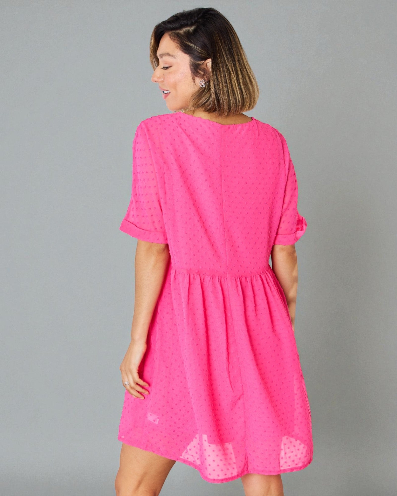 Woman wearing a bright pink dress against a gray background