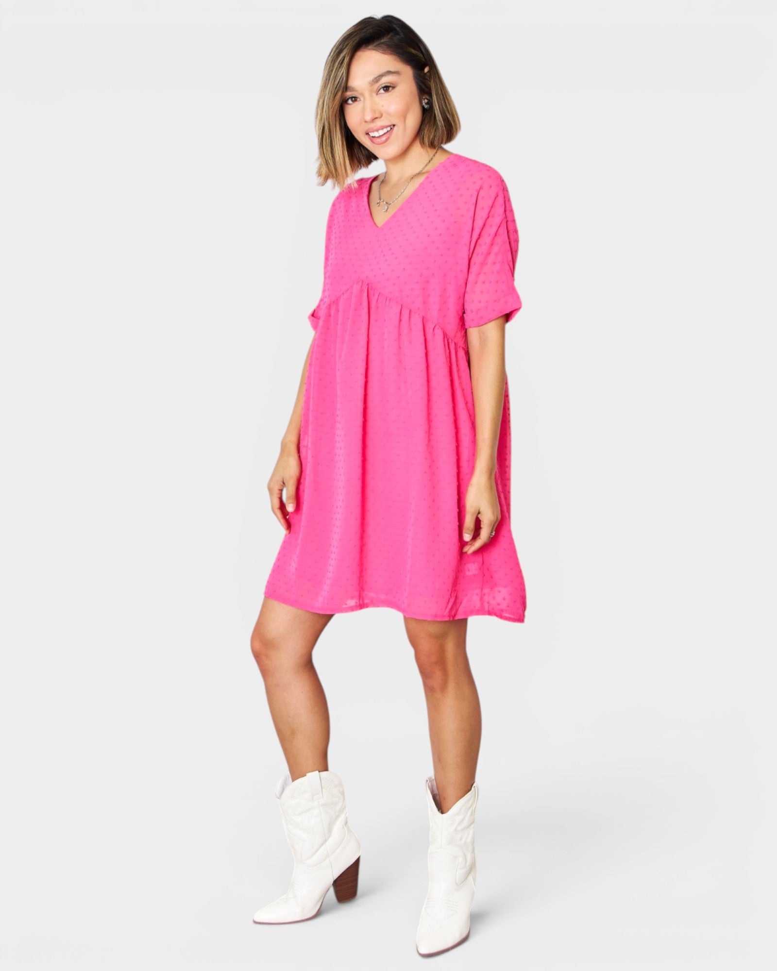 Woman wearing a bright pink dress with white boots on a white background