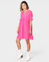 Woman wearing a bright pink dress with white boots on a white background