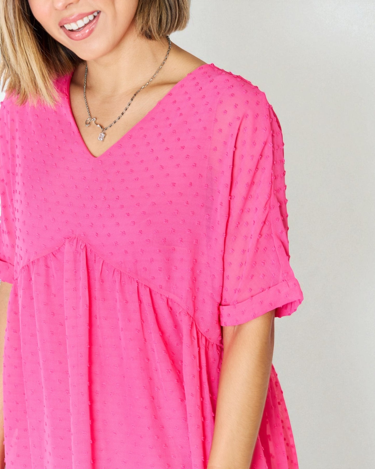 Person wearing a bright pink dress with a plain background