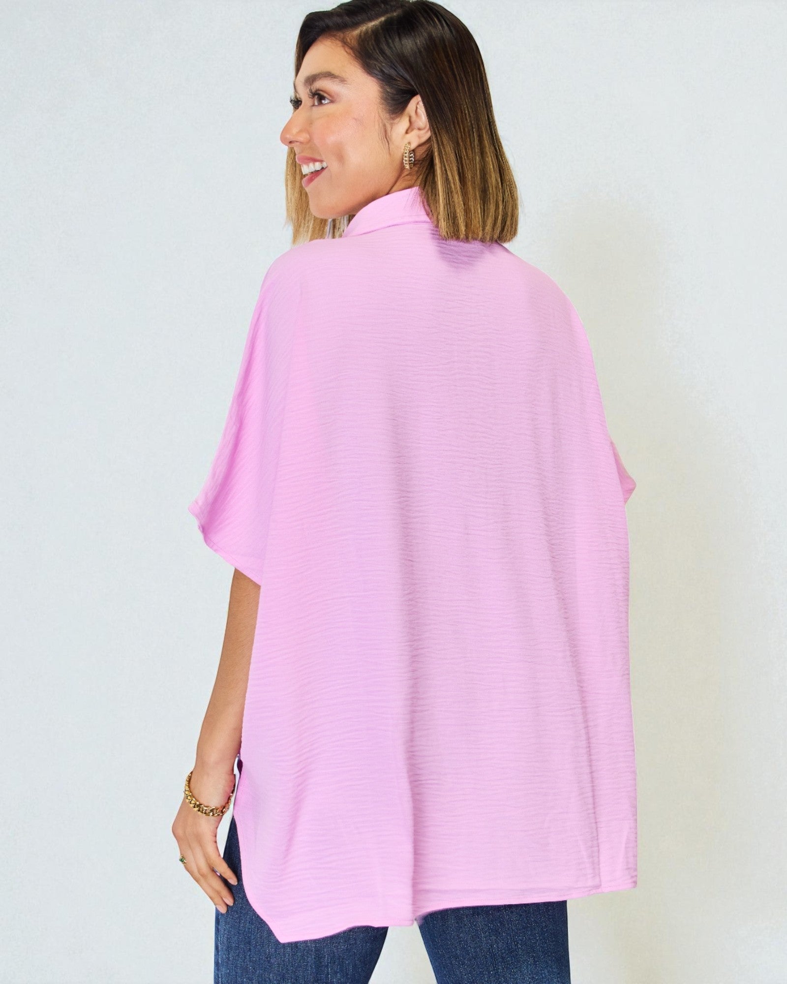 Woman wearing a pink poncho against a plain background