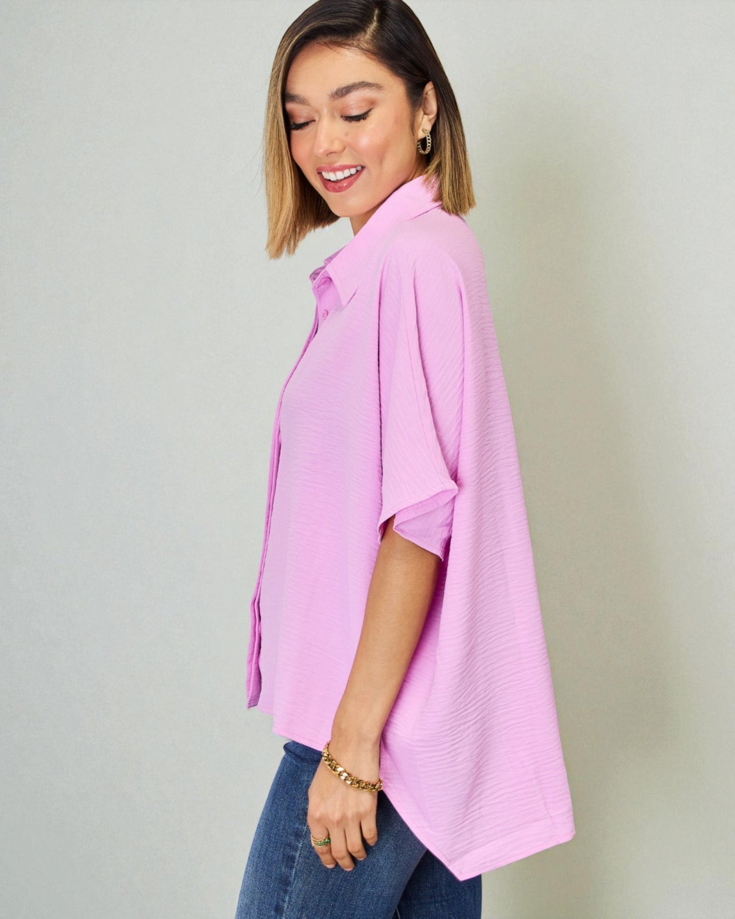 Woman wearing a pink shirt and blue jeans against a plain background
