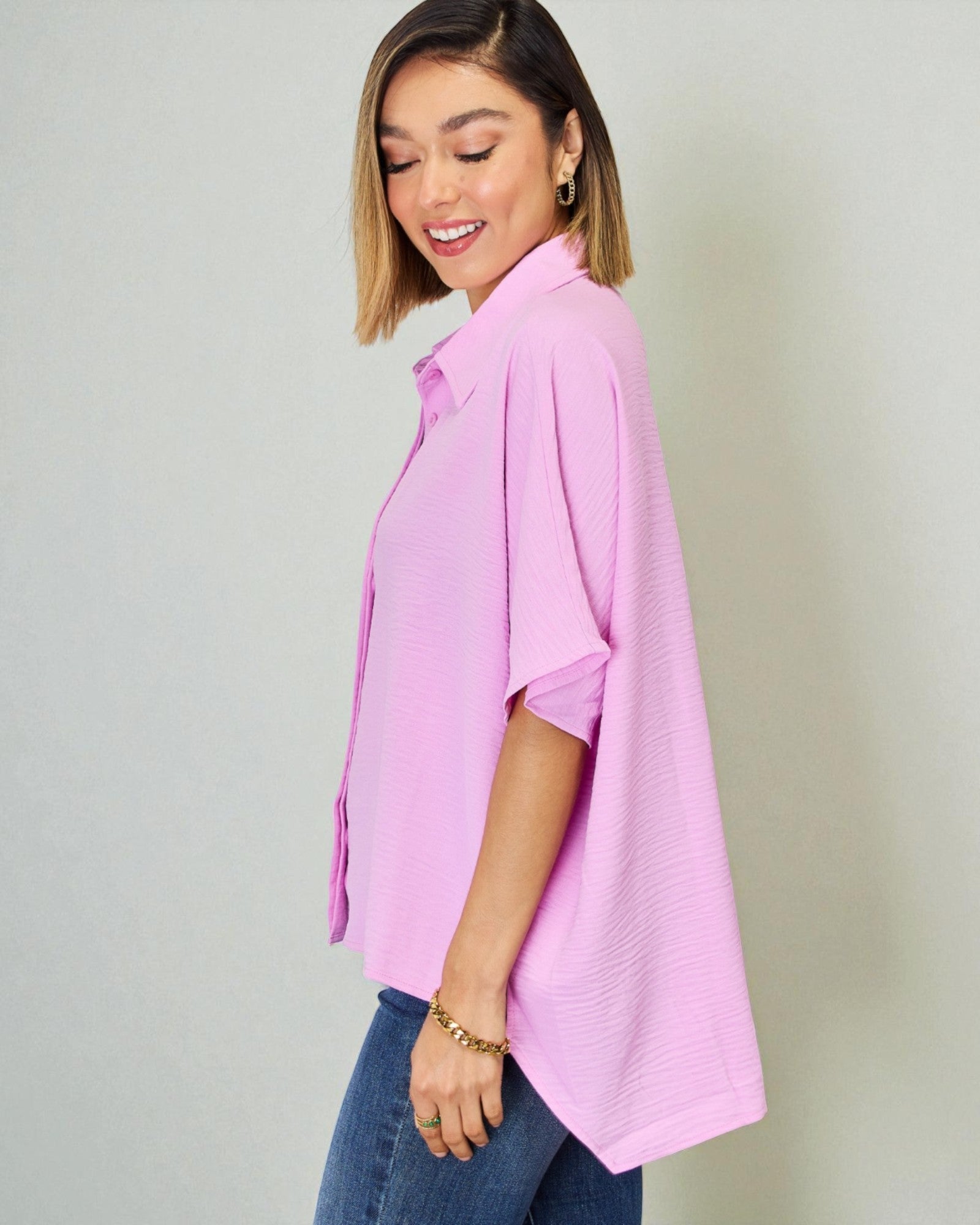 Woman wearing a pink shirt and blue jeans against a plain background