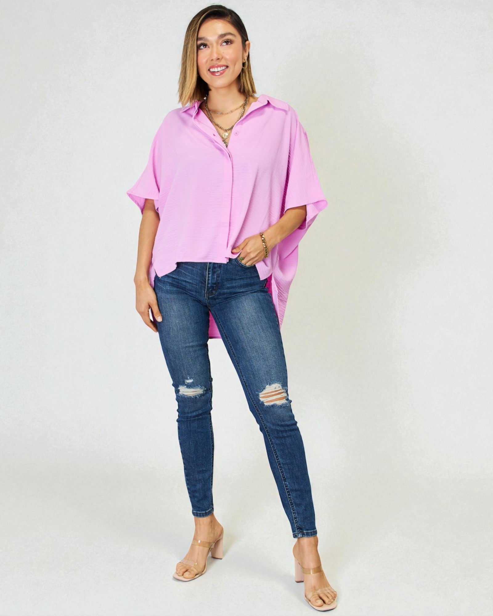 Woman wearing a pink oversized shirt and blue jeans on a white background