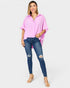 Woman wearing a pink oversized shirt and blue jeans on a white background