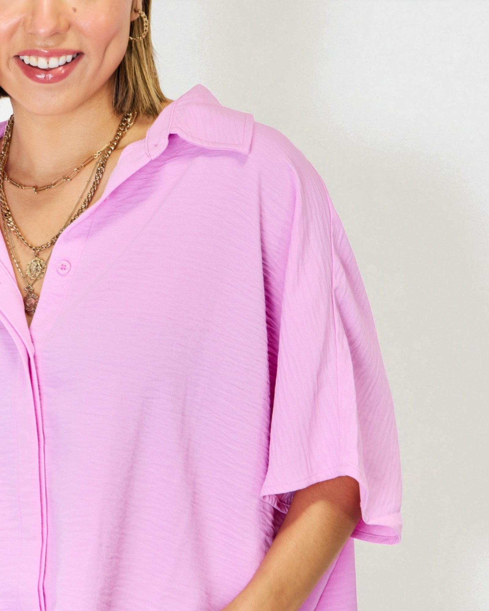 Person wearing a light pink shirt with a plain background