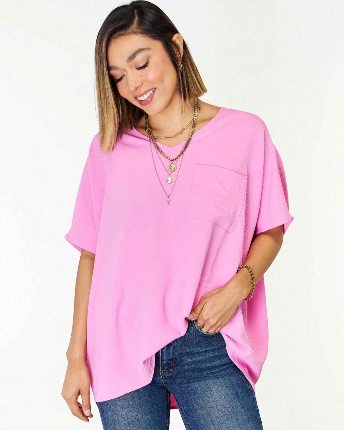 Woman wearing a pink oversized top and blue jeans on a white background