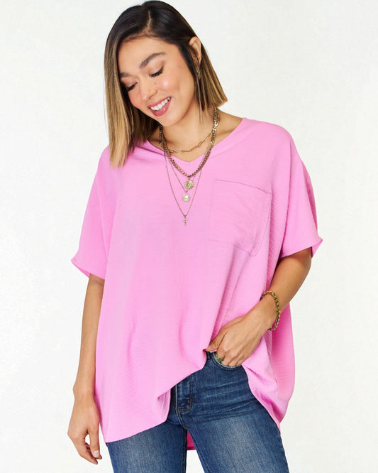 Woman wearing a pink oversized top and blue jeans on a white background