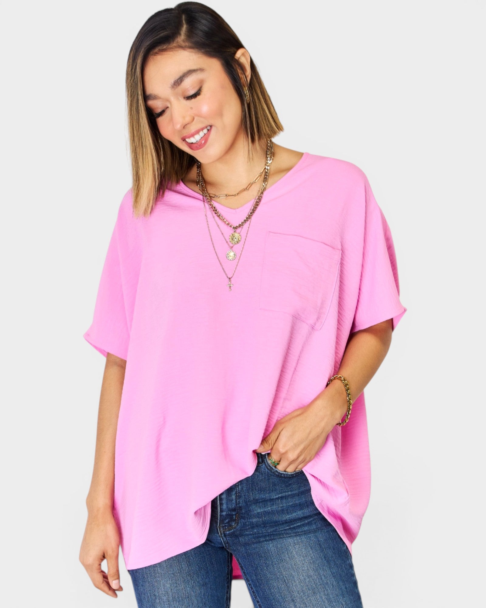 Woman wearing a pink oversized top and blue jeans on a white background