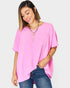 Woman wearing a pink oversized top and blue jeans on a white background