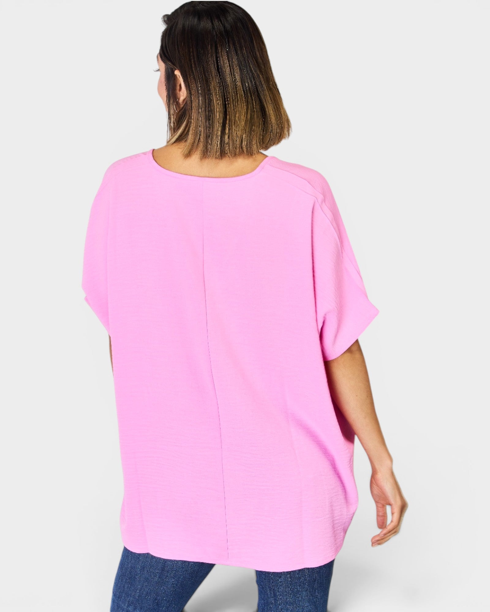 Person wearing a pink oversized top on a white background