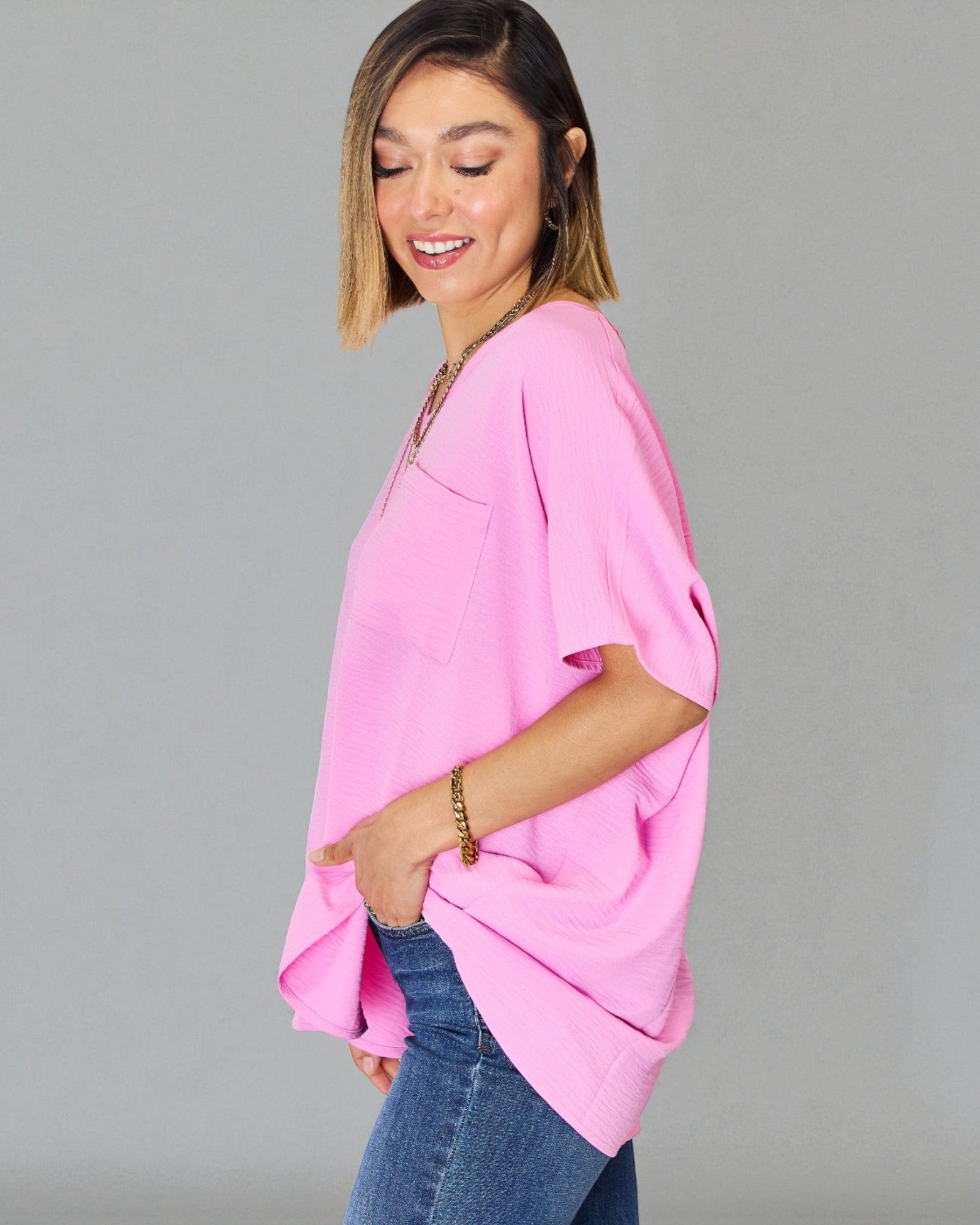 Woman wearing a pink top and blue jeans on a gray background