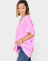 Woman wearing a pink oversized sweater and blue jeans on a white background
