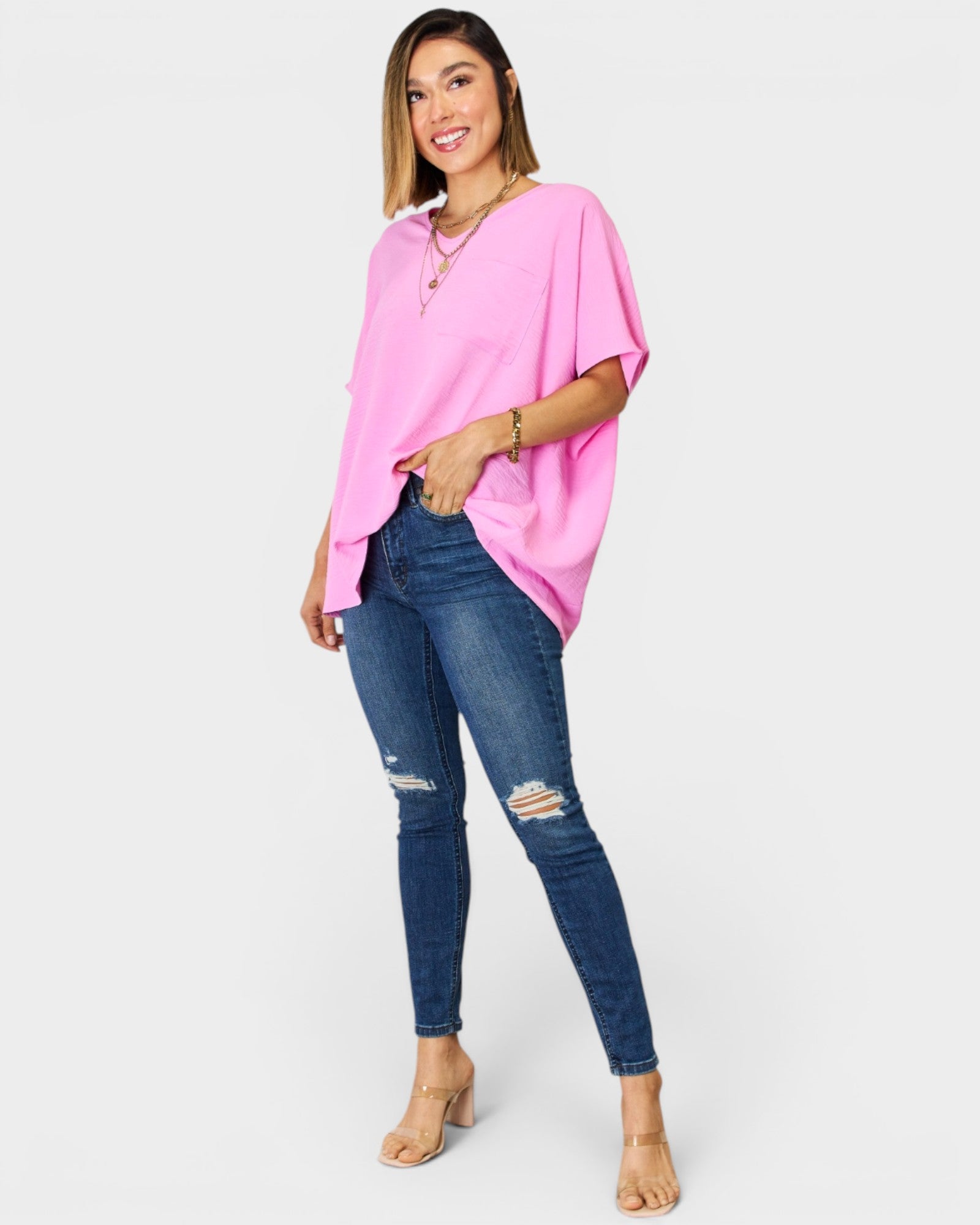 Woman wearing a pink top and blue jeans on a white background