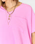 Person wearing a pink shirt with layered gold necklaces