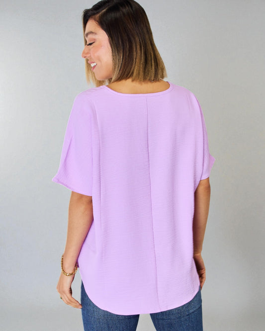 Woman wearing a light purple blouse with a plain background