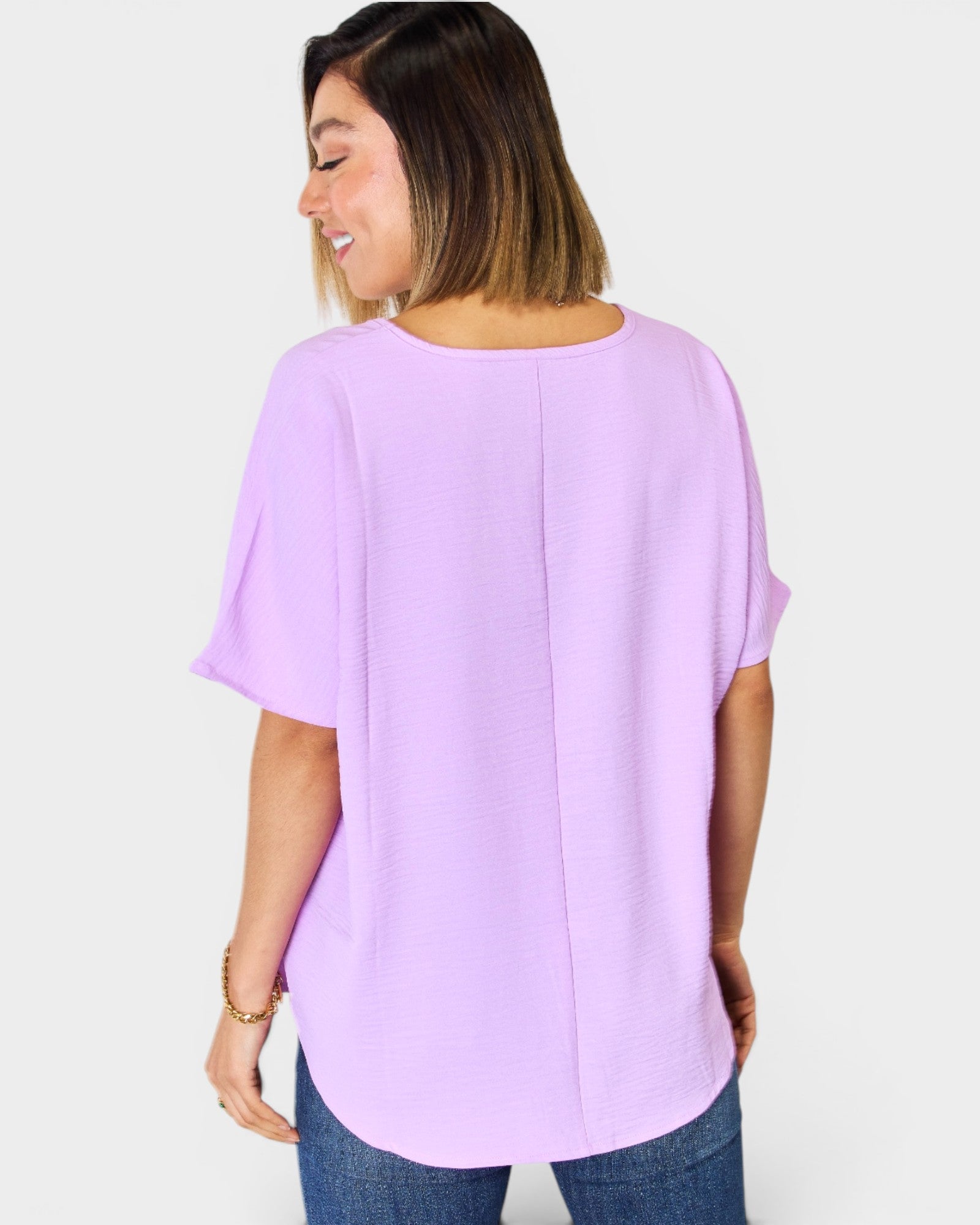 Woman wearing a light purple blouse with a plain background