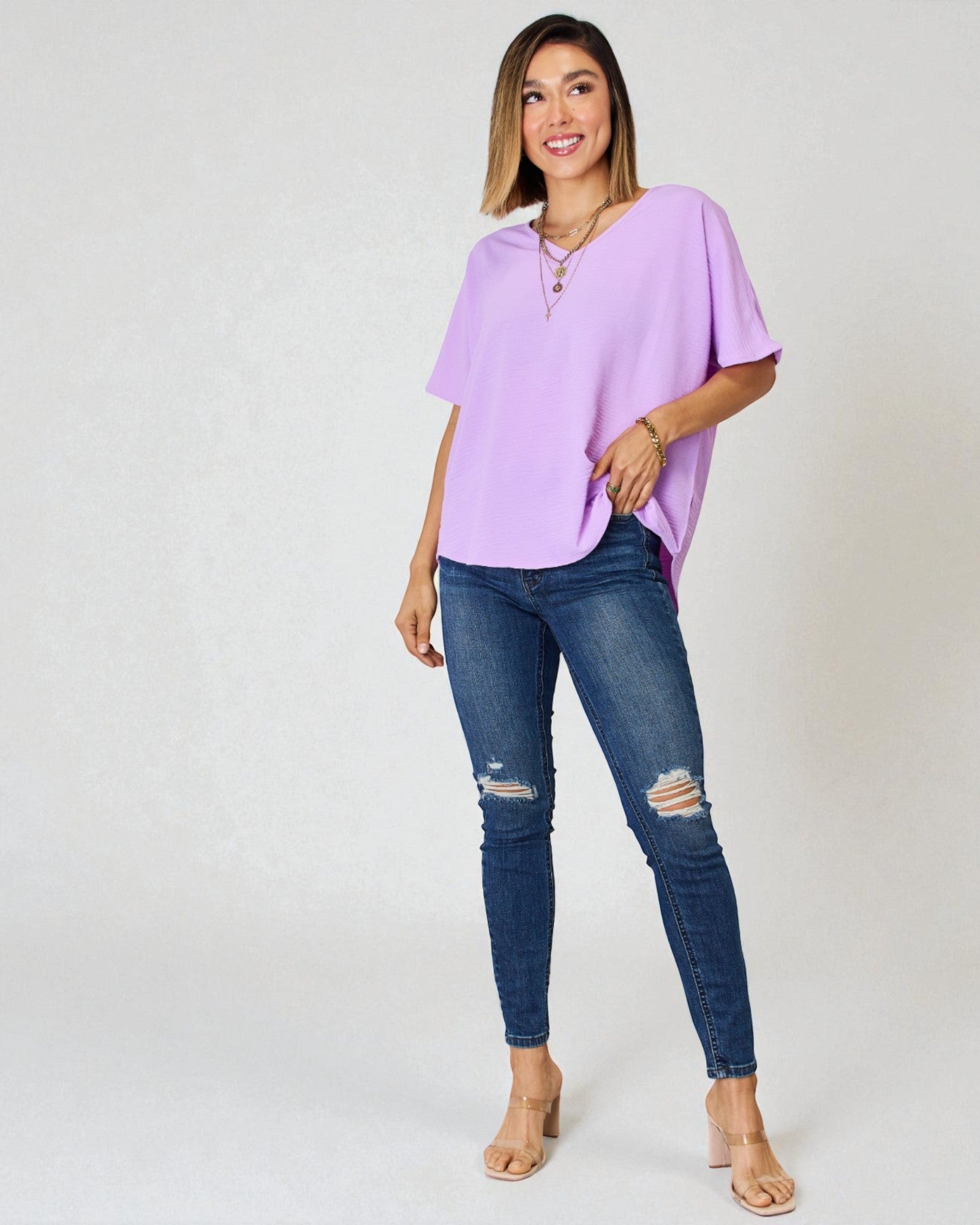 Woman wearing a light purple shirt and blue jeans on a white background
