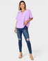Woman wearing a purple top and blue jeans on a white background