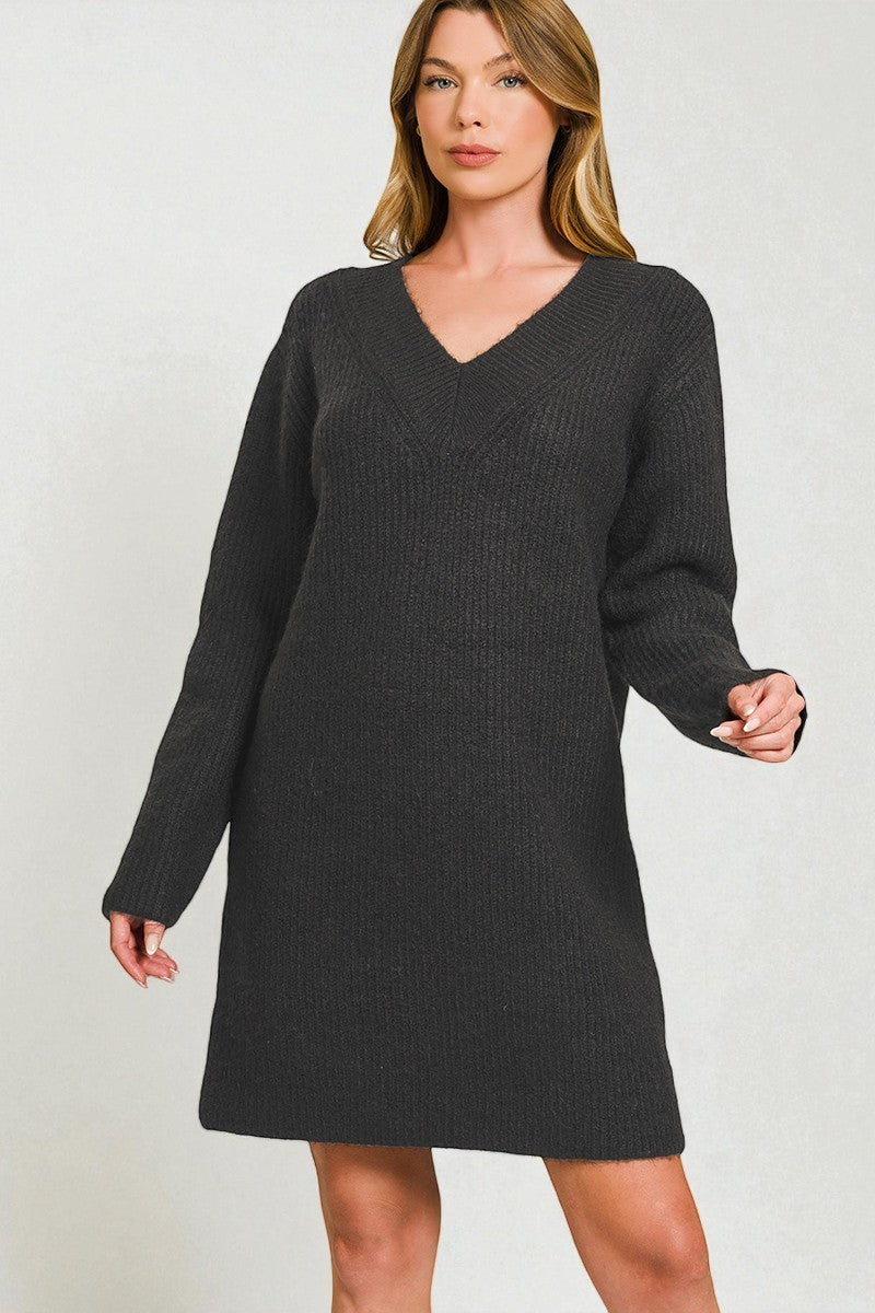 Woman wearing a black sweater dress against a plain background