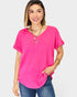 Woman wearing a bright pink top and blue jeans on a plain background
