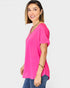 Woman wearing a bright pink top and blue jeans on a white background